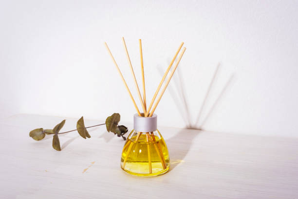 istock Glass bottle of aroma diffuser and eucalyptus branch on white wooden table. Close up 1401976903