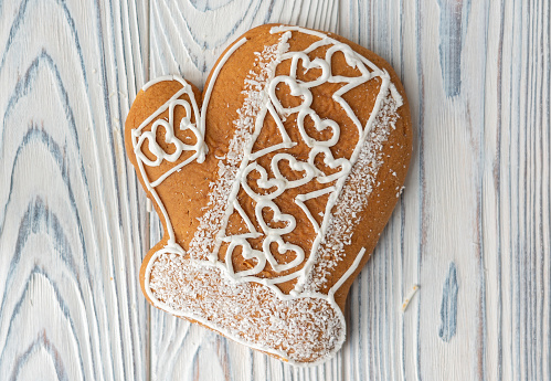 Gingerbread spice cookie in form of winter mitten with hearts.