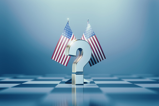 American flag pair and white question mark on a chess board. Horizontal composition with copy space and selective focus. 2022 Midterm Elections concept.