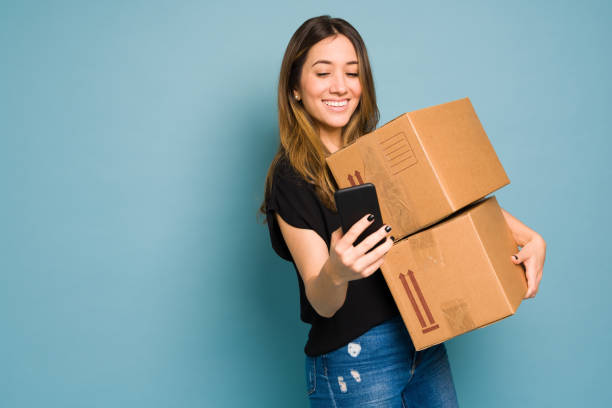 istock Young woman using an app on her smartphone to ship some packages in a studio 1401980500
