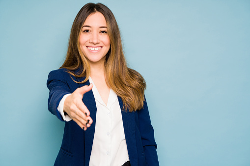 Good looking businesswoman making a deal with a handshake and smiling in a studio