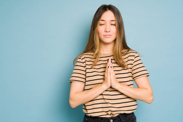 istock Woman meditating with her eyes closed in a studio with blue background 1401981823
