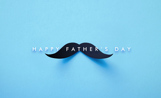 Happy Father's Day message and black mustache shape sitting on blue background. Horizontal composition with copy space. Father's Day Concept.