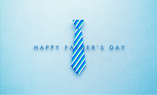 Happy Father's Day message sitting over blue striped necktie on blue background. Horizontal composition with copy space. Father's Day Concept.