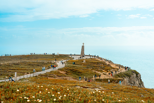 View of the Cabo da Roca monument. Sintra, Portugal. Portuguese Farol de Cabo da Roca is a cape which forms the westernmost point Eurasian land mass. Sunny summer day. Cloudy sky