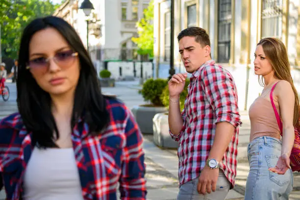 Disloyal man walking with his girlfriend and looking amazed at another seductive girl