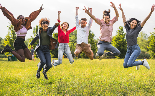 Group of happy friends jumping in the park outdoor - Young student celebrating  finish of university