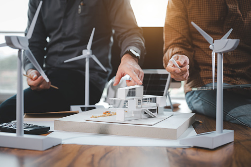 Two engineer design professionals discussion about calculate to use pure energy nature and Installing solar panels on roof house to generate electricity working with model, and Solar panel sample