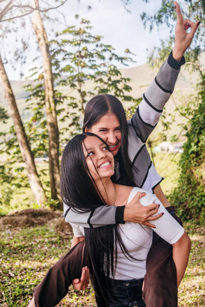 Friend carrying another on her back as they both smile happily on a sunny day