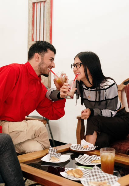 istock Couple smiling and looking at each other while drinking and intertwining arms. 1401993683