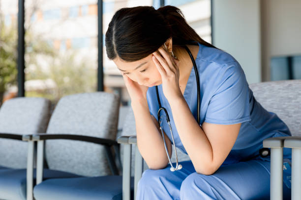 istock Exhausted female doctor holds head in hands 1401996435