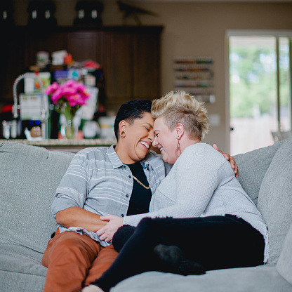 Lifestyle portraits of a lesbian couple in love in their home. They are a multi racial couple, in their 30s.