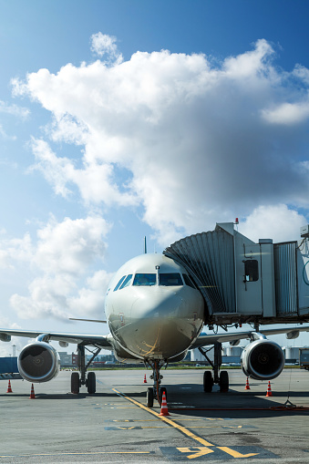 Passenger airplane on the airfield docked with passenger boarding bridge. Preparations of the airplane at the airport terminal.