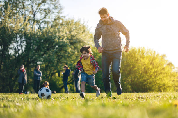 istock Boy playing soccer with father at public park at sunset 1401998718