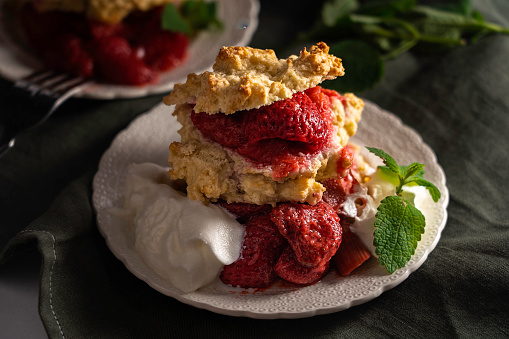 Seasonal spring dessert: Strawberry and rhubarb shortcake garnished with whipped cream and mint