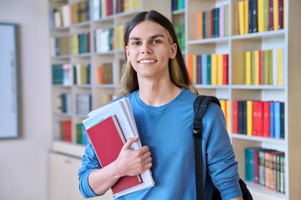 istock Portrait of a student guy with textbooks looking at camera in college library 1402005870