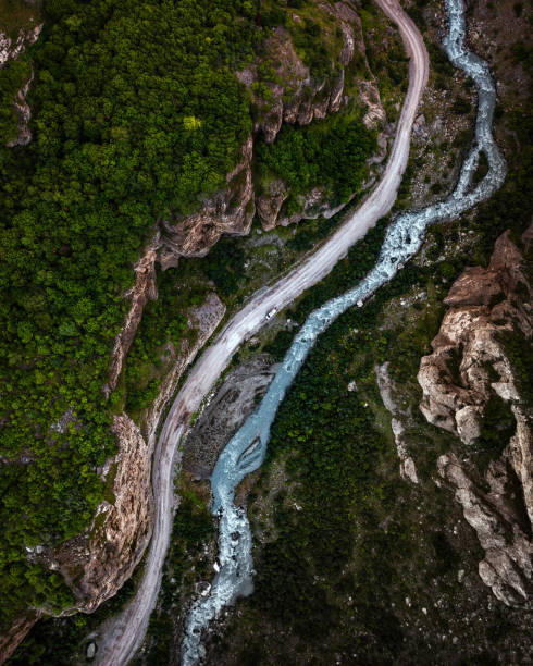 istock Top view of mountain road in forest with blue river 1402009587