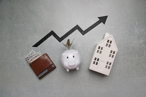 Home budget planning. Cost of living. Inflation concept. Concept of saving money for buying new house. Piggy bank, wallet with dollar banknotes and model of house.