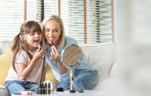 istock Happy Mother and little Daughter playing applying lipsticks. 1402013261