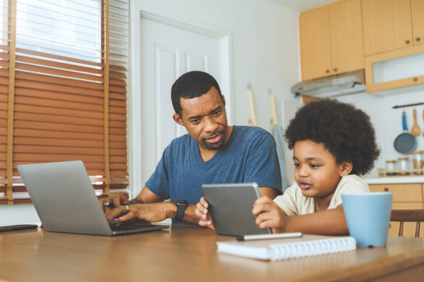 istock African American father working on laptop while Little son studying on digital tablet 1402013300