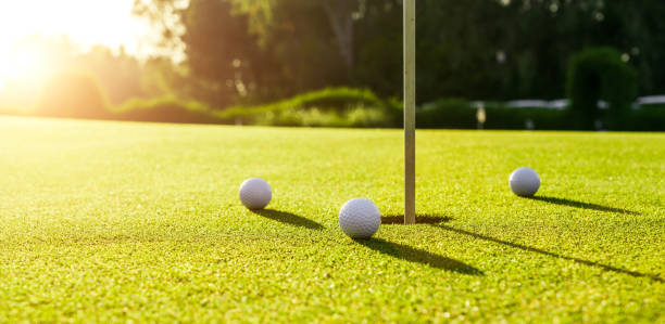 istock Three golf balls on the green grass near hole on a golf course at sunset 1402013699