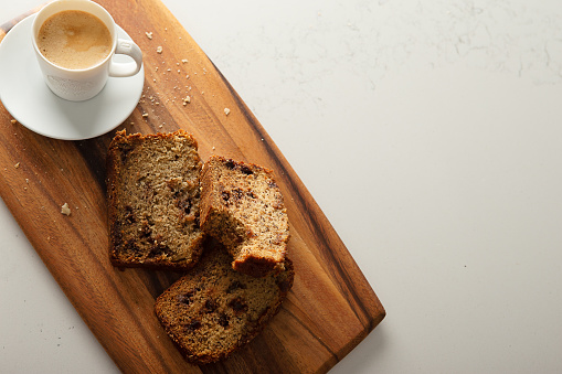 Espresso coffee and Slices of banana bread aon wooden cutting board on quartz kitchen counter top