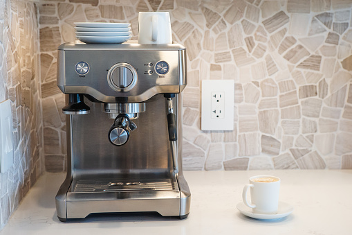 Coffee machine with a cup of espresso sitting on quartz kitchen counter.