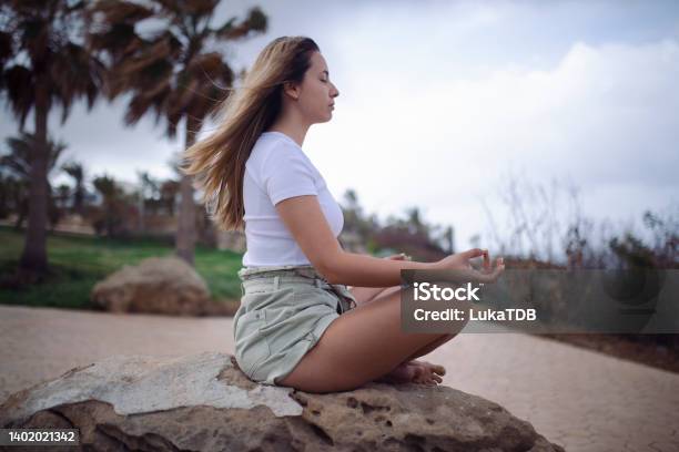 A Side View Of A Woman Meditating And Thus Relaxing Her Mind And Body Stock Photo - Download Image Now