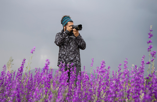 Male photographer taking landscape pictures on the field in nature