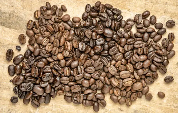 sampler of coffee beans from different parts of the world - overhead view against handmade textured paper