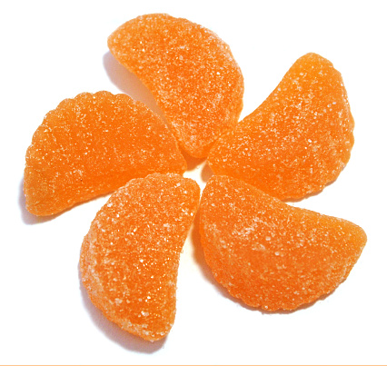 Candy Orange Slices - sugar covered orange gummy candy shaped like orange slices with white background - arranged
