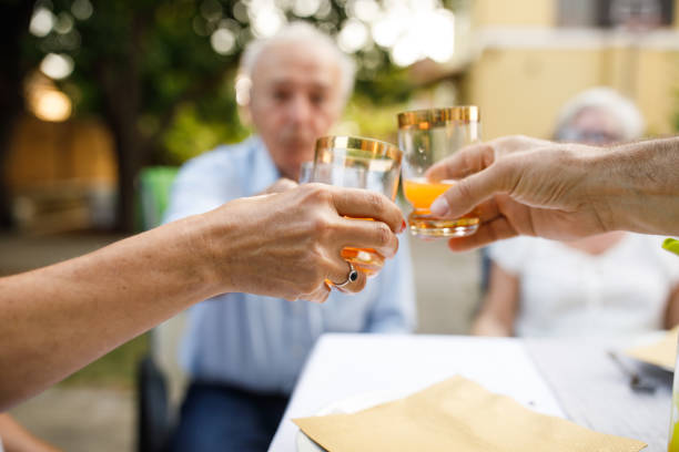 Close up shot of unrecognizable woman making celebratory toast with two of her friends during a relaxing summer dinner party in the back yard.