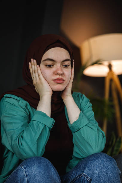 istock Distraught young woman sitting with head in hands, contemplating 1402045657