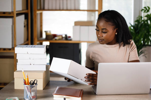 istock Young businesswoman looking at package label while preparing it for shipping 1402045794