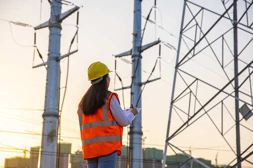Women electrical engineer while working near to high voltage tower