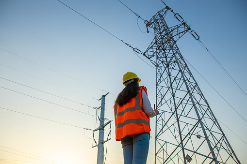 Female engineer working near high-voltage tower