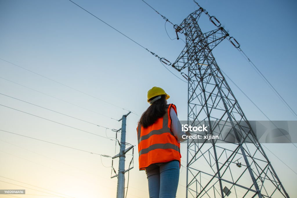 Female engineer working near high-voltage tower Female engineer working at a electrical pylons translation Electricity Stock Photo