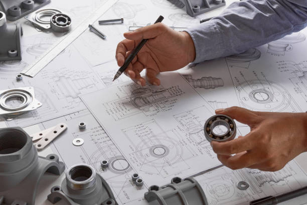 Engineer technician designing drawings mechanicalÂ parts engineering Engine
manufacturing factory Industry Industrial work project blueprints measuring bearings caliper tools stock photo