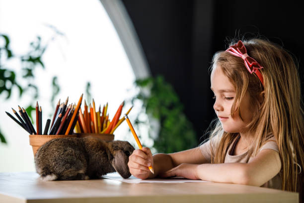 istock Adorable bunny rabbit exploring what little girl is drawing 1402049257