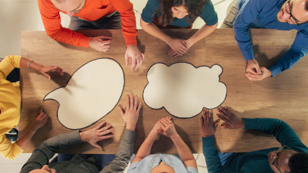 istock Blank thought bubbles on a conference table with business people sitting around, having a meeting 1402049477