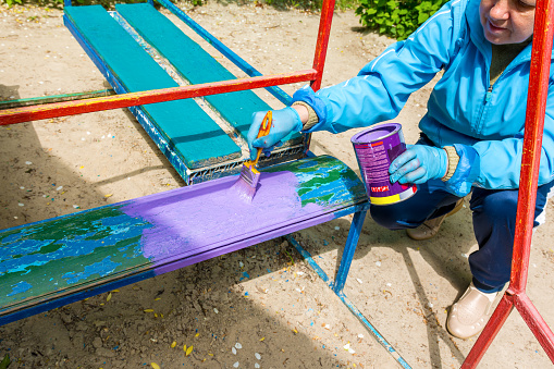 Chelyabinsk Russia June 4 2022 a woman paints a bench on a playground in a kindergarten