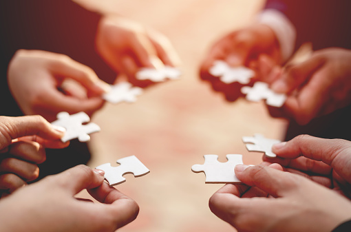 Close-up of a businessman with puzzle pieces in his hands arranged together. teamwork unity in teamwork The concept of combining physical strength and power at work.