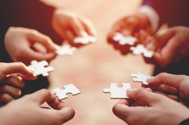 success Close-up of a businessman with puzzle pieces in his hands arranged together. teamwork unity in teamwork The concept of combining physical strength and power at work. cooperation stock pictures, royalty-free photos & images