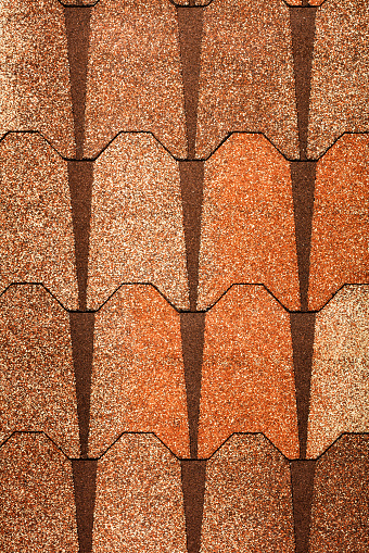 Background and texture of brown bituminous roof tiles with stone hydrophilic coating. Vertical image. Copy space.