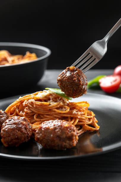 istock fork with a meat ball. Pasta with meat balls on a black plate 1402058261