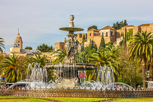 Malaga, Spain - May 20, 2022: Malaga street fountain and Alcazaba fortress.