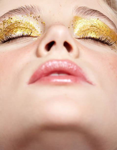 primo piano macro scatto di viso femminile umano chiuso con trucco di bellezza giallo occhi fumosi. - glitter make up eyelash human face foto e immagini stock