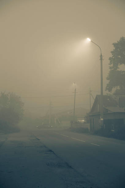 estrada na cidade em uma noite escura com neblina pesada, iluminada por luzes de rua led - spooky horror nostalgia autumn - fotografias e filmes do acervo