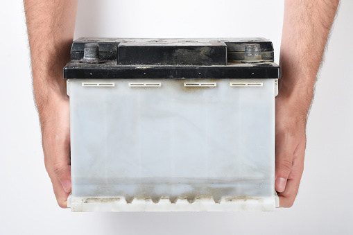 Hand holding old car battery, repairman holding old car battery on the white background