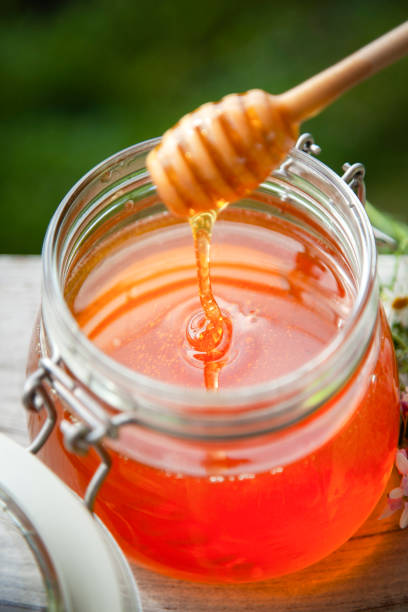 istock Honey in glass jar on a wooden floor. 1402063406